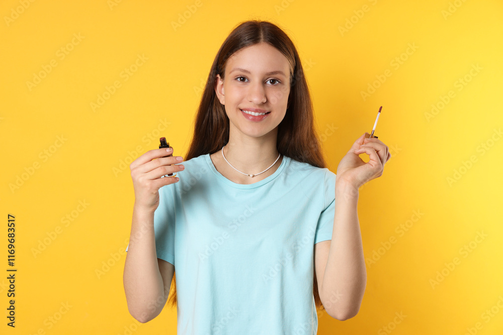 Smiling teenage girl with lip gloss on yellow background Smiling teenage girl with lip gloss on yellow background