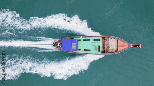 An aerial photograph captures a longtail boat gliding through the clear turquoise waters of Krabi, Thailand, showcasing the stunning natural beauty of this remarkable area