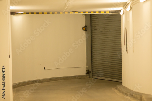 This is an image showcasing the entrance of a parking garage, characterized by its gray concrete structure and a rolling roller shutter door photo