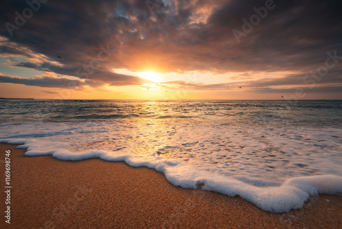 Fototapeta Naklejka Na Ścianę i Meble -  Close up of waves on the beach and a beautiful sunrise over the sea