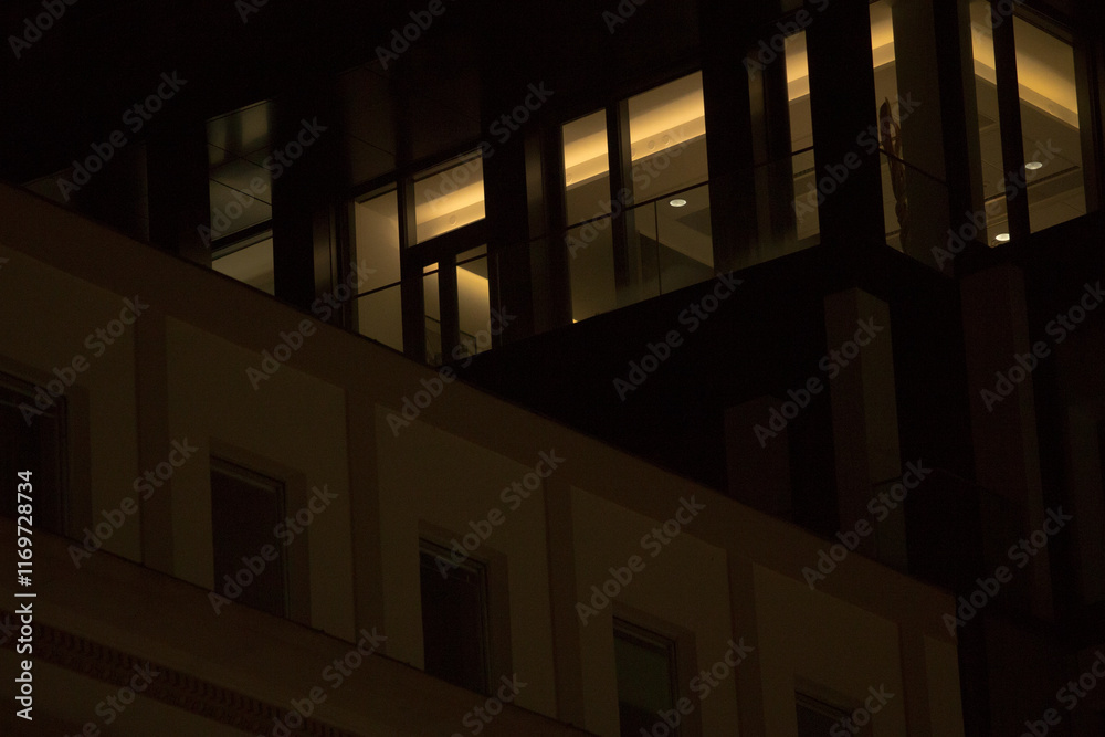 Fototapeta premium At night, the building with numerous windows becomes fully illuminated, creating a stunning visual effect against the dark sky