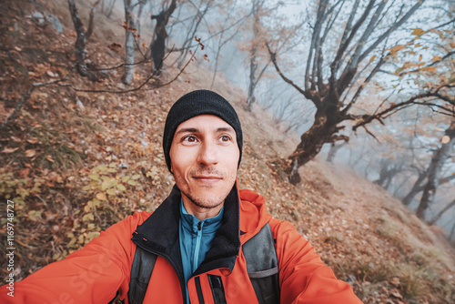 Young hiker taking a selfie while enjoying a foggy autumn day in the woods photo