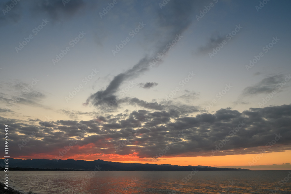 Obraz premium Breathtaking sunset over tranquil waters with dramatic clouds reflecting vibrant colors