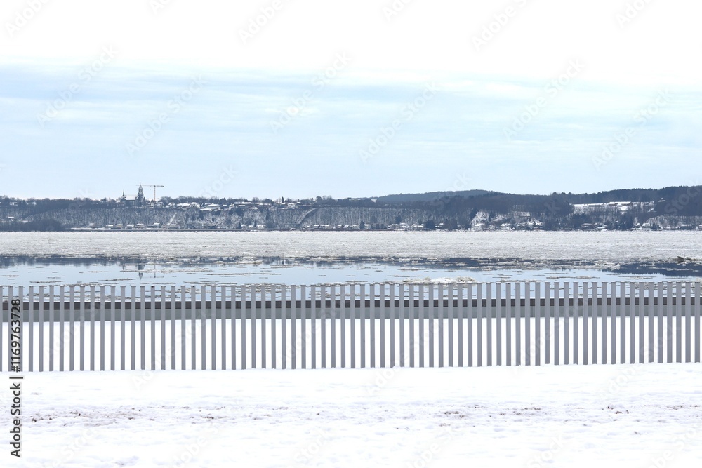 A riverside in winter with a wooden fence. A coastline and a river with icebergs and snow. The St-Laurent river in Quebec and December calendar. A riverside in winter with a wooden fence. A coastline and a river with icebergs and snow. The St-Laurent river in Quebec and December calendar.