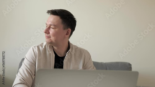 Man is using laptop working at home. Young remote worker. Work online, digital, IT, remote concept. Focused business man looking at window on rest break. 