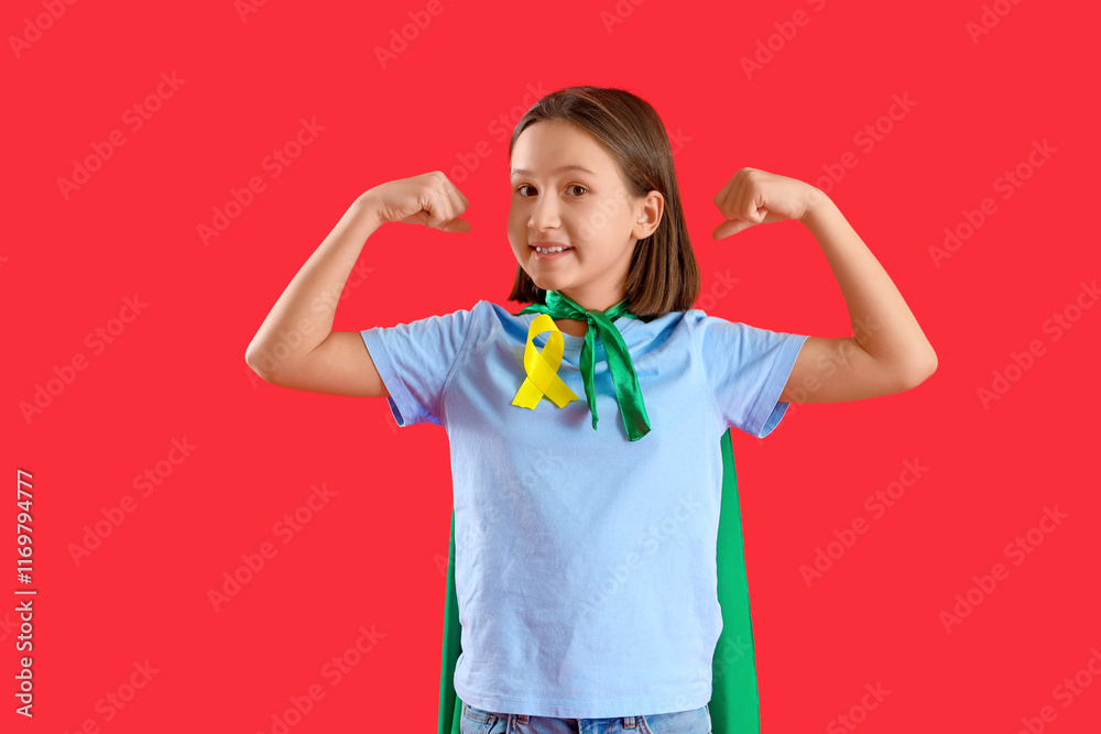 Little girl dressed as superhero with gold ribbon showing muscles on red background. Childhood cancer awareness concept Little girl dressed as superhero with gold ribbon showing muscles on red background. Childhood cancer awareness concept