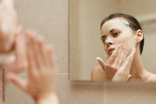 Young woman applying facial cleanser in bathroom mirror, focusing on skincare routine and self-care practices, natural setting promoting wellness and beauty. photo