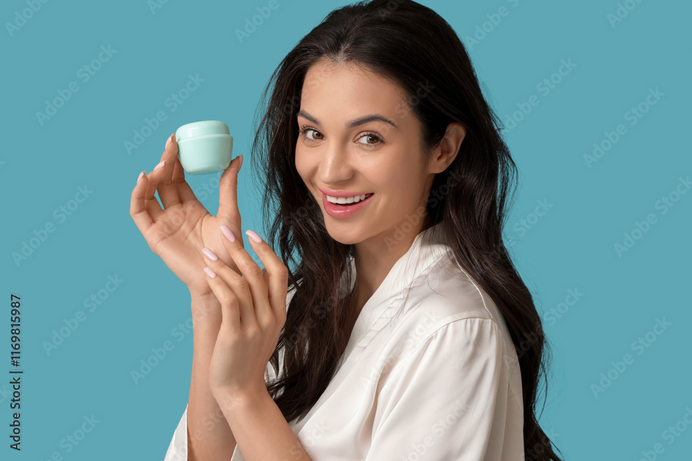 Beautiful young happy woman in robe with jar of cream on blue background Beautiful young happy woman in robe with jar of cream on blue background