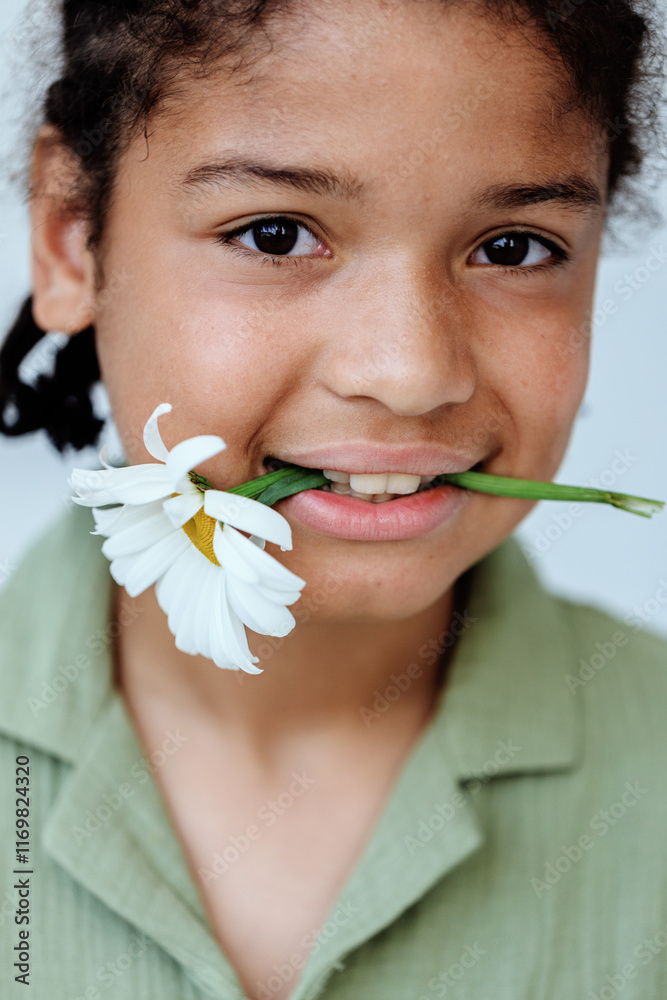 Joyful young boy playfully holding a flower in his mouth and smiling brightly Joyful young boy playfully holding a flower in his mouth and smiling brightly