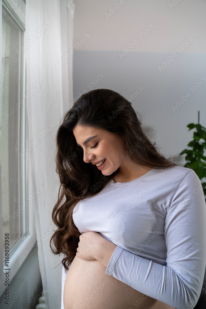 Closeup shot of beautiful natural long hair pregnant woman, looking at her belly and smiling Closeup shot of beautiful natural long hair pregnant woman, looking at her belly and smiling