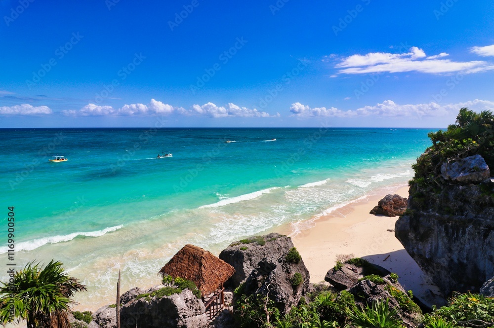 Fototapeta premium Beautiful sea views of the turquoise blue green waters of the Caribbean Sea with a viewing deck leading to the playa ruinas, or ruins beach at the late 13th century Mayan ruins of Tulum,Mexico