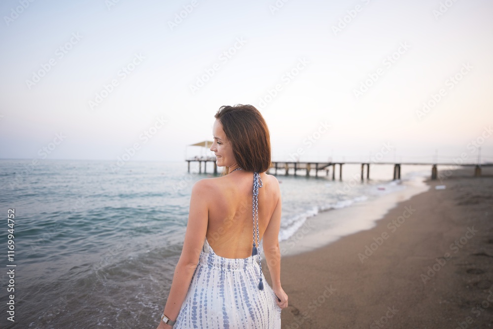 Woman Enjoying Peaceful Beach Sunset in Summer Dress with Ocean and Pier View Woman Enjoying Peaceful Beach Sunset in Summer Dress with Ocean and Pier View