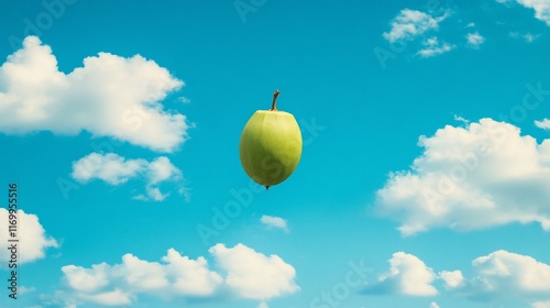 A lime green apple-like fruit floats in the air against a vibrant blue sky dotted with fluffy white clouds. photo