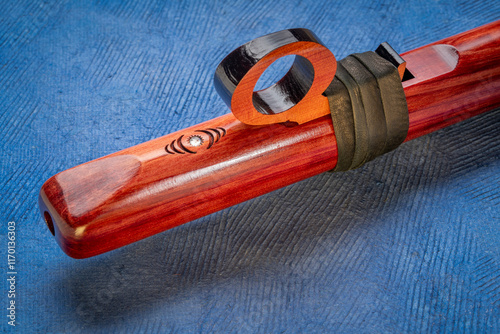 detail of native American style flute with fetish handcrafted from aromatic cedar wood against art paper photo