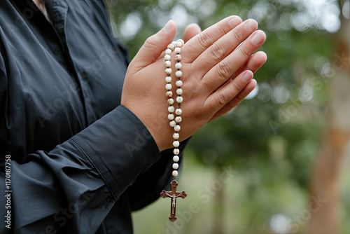 Hands engaged in prayer while holding a rosary photo