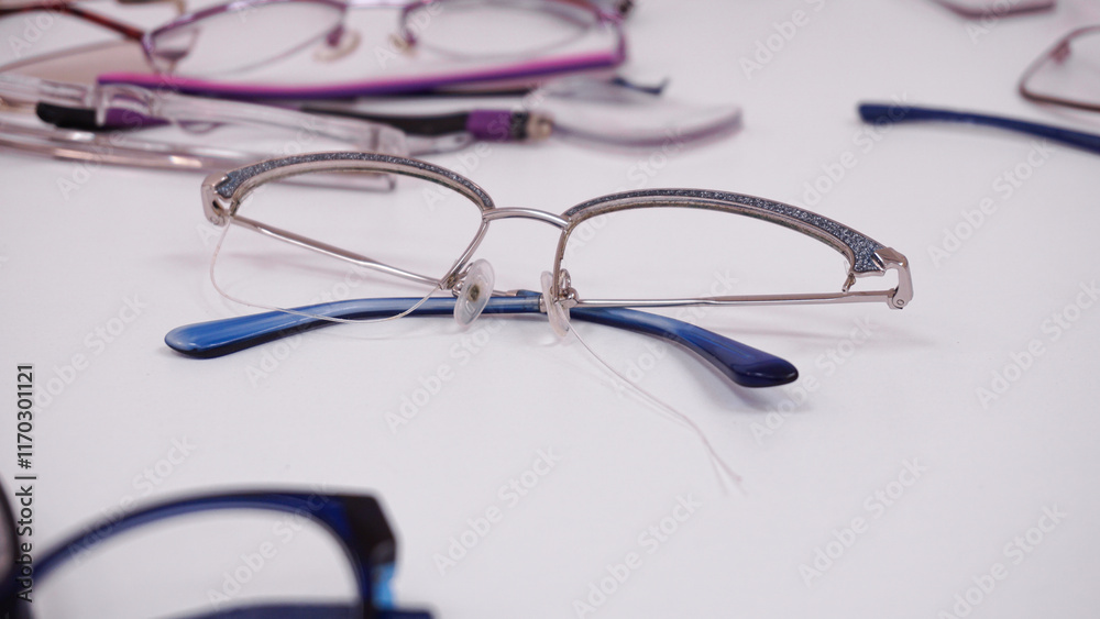 Assortment of broken glasses, broken hinges, missing lenses, cracked frames, deformed glasses. Mix of optical eyeglasses. Workstation for optical technician or optician Assortment of broken glasses, broken hinges, missing lenses, cracked frames, deformed glasses. Mix of optical eyeglasses. Workstation for optical technician or optician