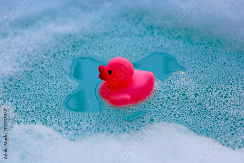 Pink rubber duck on water with soap foam