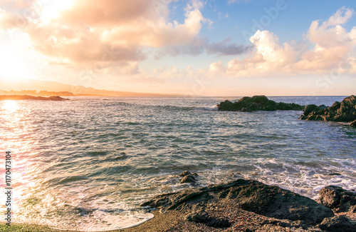 beautiful coast beach with sea gulf water during sunset or sunrise with golden sand, nice black rocks and stones, colorful vawes and clouds in thr sky photo