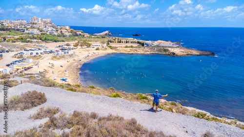 Tourist admiring cala reona beach and mediterranean sea in la manga, spain photo