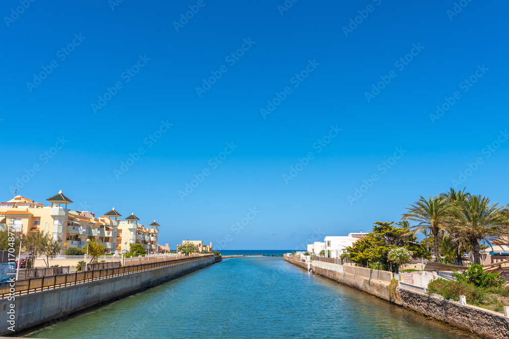 Fototapeta premium Canal flowing between buildings in la manga del mar menor, spain