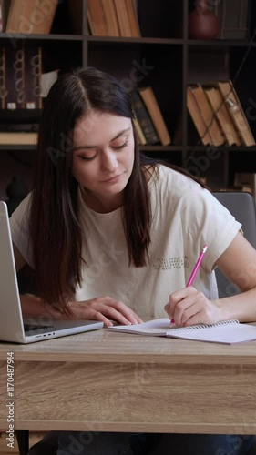 Woman student notes academic information looking at laptop