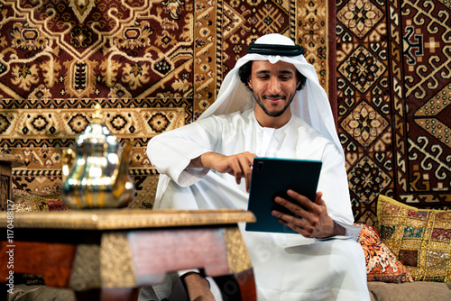 Man from emirati wearing kandura outfit spending time in an arabian traditional house in Dubai.