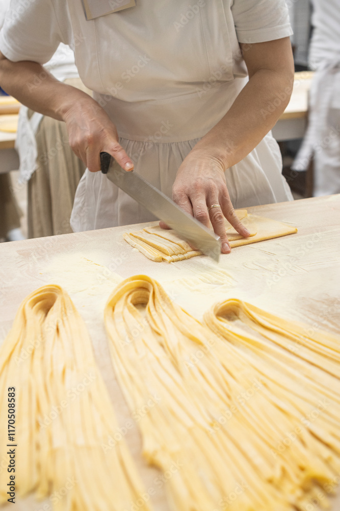 Traditional italian cook cutting pasta. Delicious homemade cuisine. Tagliatelle