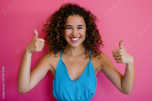 Young woman gives two thumbs up, smiling brightly.