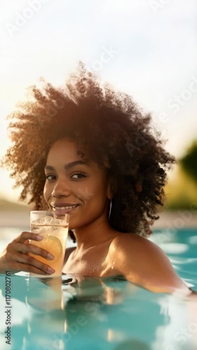 African American woman having a drink while enjoying the pool at sunset