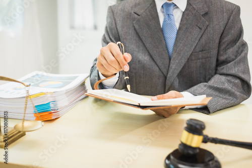 Schilderij op canvas Male lawyer diligently examines documents placed on his desk, demonstrating his professionalism and dedication to finding legal truth, analyzing ideas, and pursuing justice with relentless focus