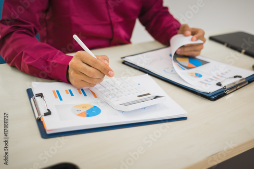 A focused man works diligently in his office, reviewing numerous accounting documents on his desk. His goal is to ensure accuracy and precision, avoiding errors in critical financial data.