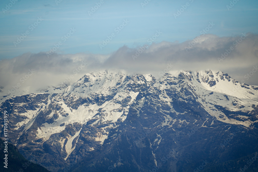 Fototapeta premium Snow covered rocky mountain peaks with low clouds, Switzerland