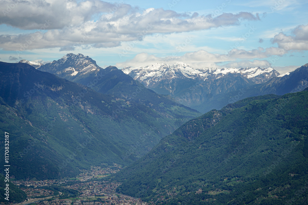 Naklejka premium Snow covered Swiss Alps with Bellinzona Town in the valley and cloud covered blue sky, Switzerland