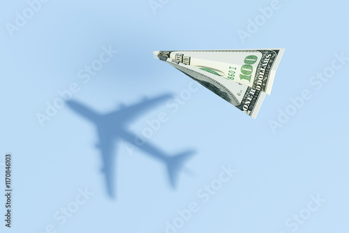 Paper plane made of a US 100 dollar bill flying over a blue sea background and projecting a realistic commercial flight shadow. Illustration of the concept of travel budget and air ticket prices