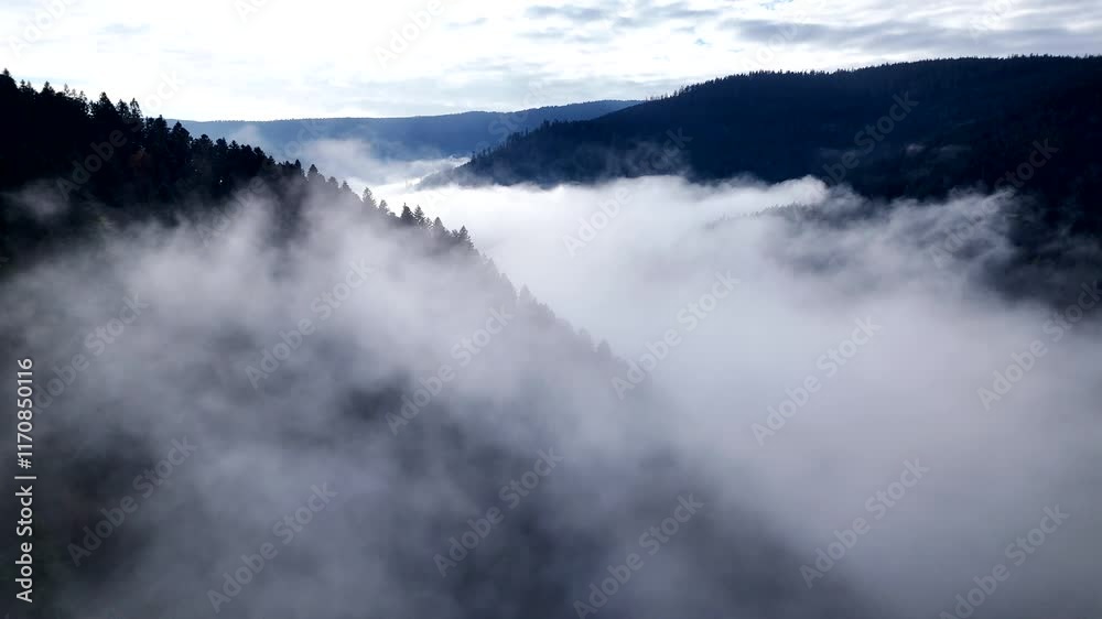 Aerial slow orbiting fly over a sea of clouds of a mountain valley