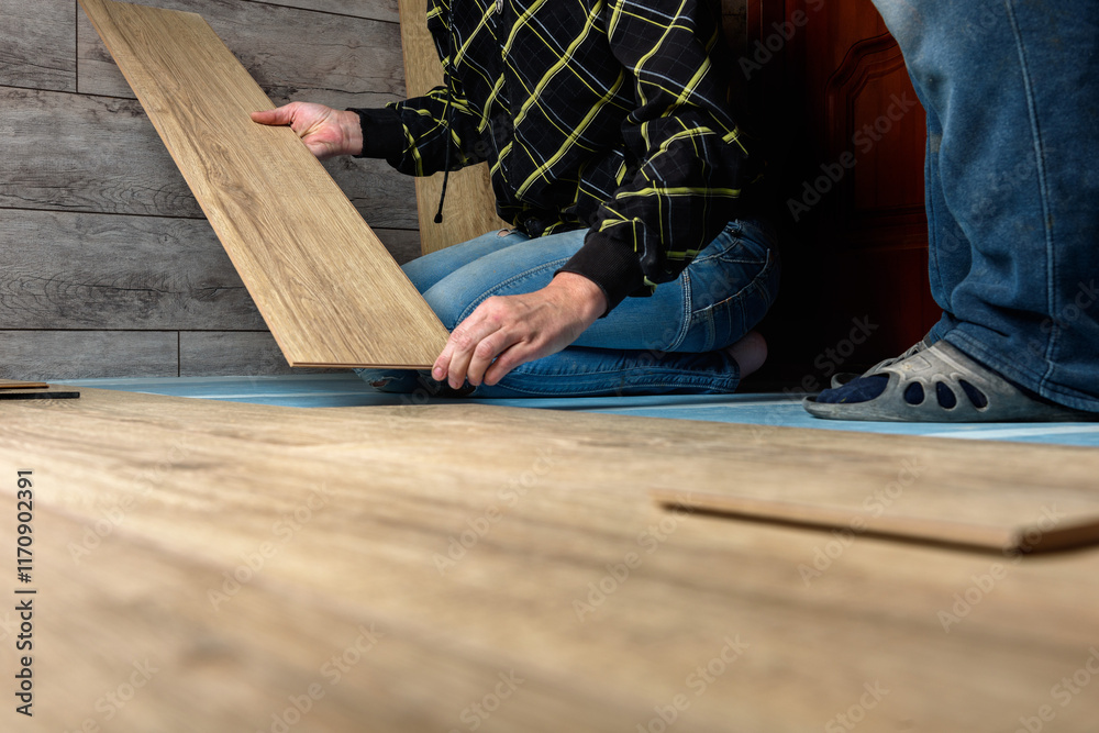 Worker installing laminate flooring in apartment under renovation. Worker installing laminate flooring in apartment under renovation.