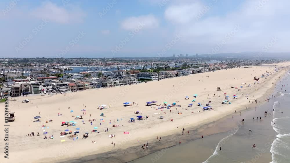 Newport Beach , California on a sunny day with people along the sandy shore - aerial flyover Newport Beach , California on a sunny day with people along the sandy shore - aerial flyover
