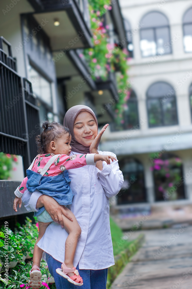 A joyful asian woman wearing hijab embraces a child in a beautiful outdoor setting, surrounded by flowers. A joyful asian woman wearing hijab embraces a child in a beautiful outdoor setting, surrounded by flowers.