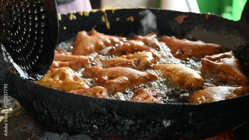 Bread pakora is being fried in hot oil. It is made by stuffing the bread with potatoes and dipping it in the batter of chickpea flour and then frying it. popular snack of India. Indian street food. 