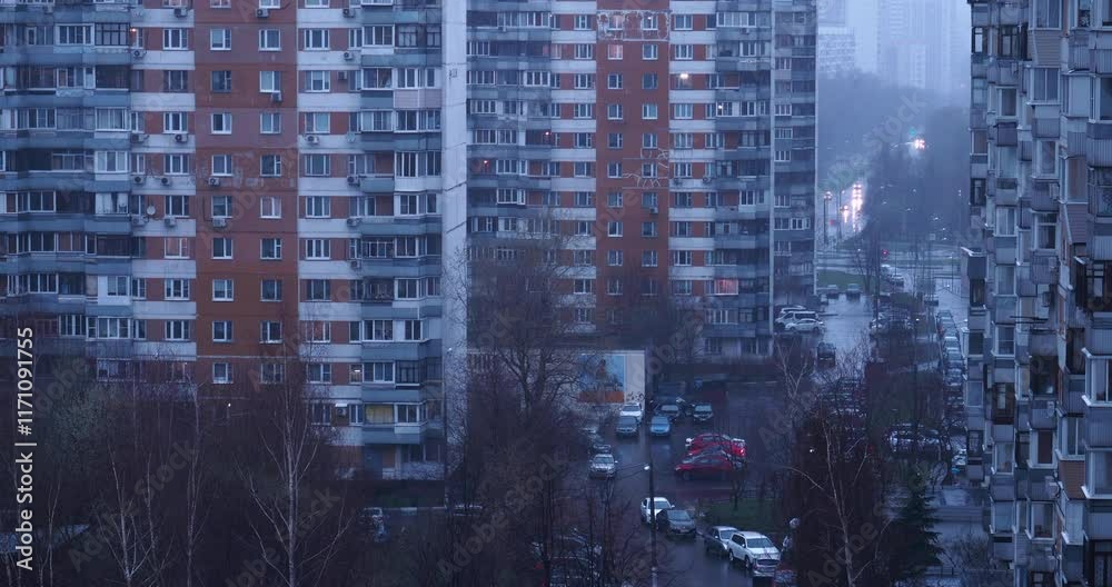 A view from the window reveals a rainy street with parked cars and an apartment building typical of Eastern Europe, creating a somber and melancholic atmosphere