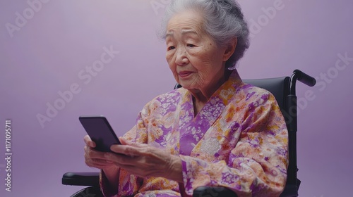 Elderly Woman in Traditional Kimono Using Smartphone Against Pastel Purple Background in a Wheelchair photo