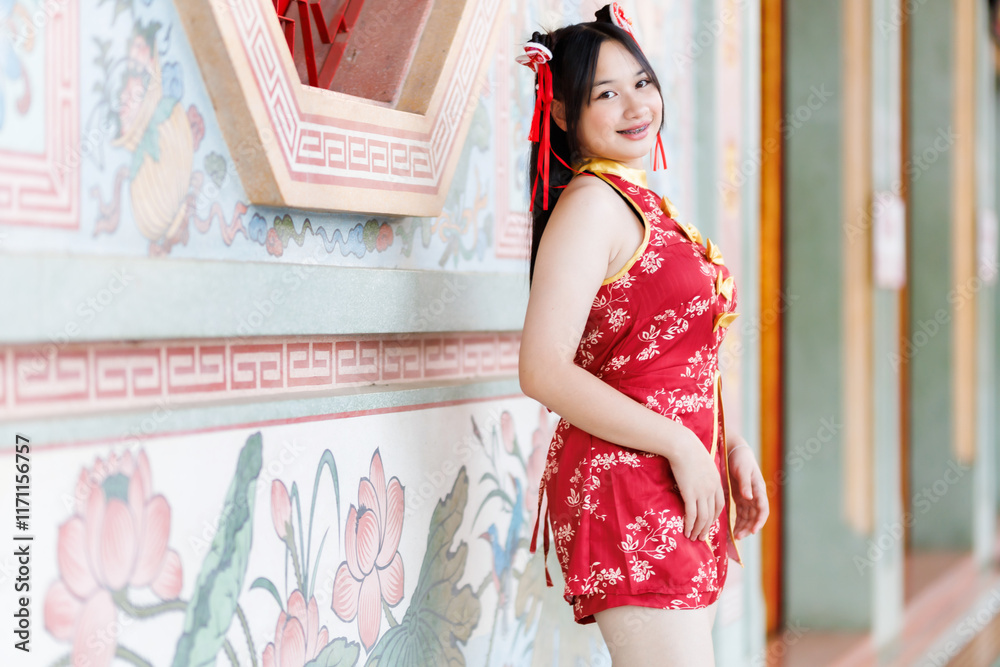 Portrait beautiful cute smiles Asian young woman wearing red cheongsam dress traditional decoration for Chinese new year festival celebrate culture of china at Chinese shrine Public places in Thailand