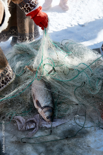 Ice fishing on a frozen lake in cold winter photo