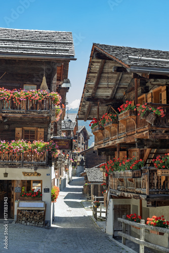 Village traditionnel valaisan de montagne avec des vieux chalets en bois et des géranium aux balcons photo