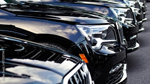 Reflection of clouds on glossy black cars parked in an outdoor lot photo