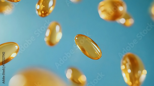 Floating capsules of golden oil hover against a soft blue backdrop, creating a visually appealing and vibrant display of health supplements in motion photo