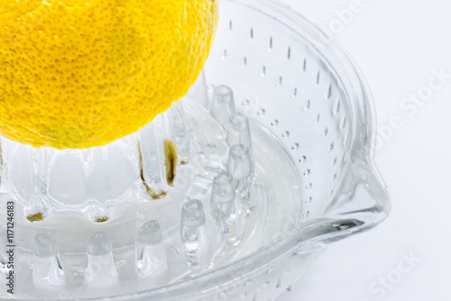 Glass Lemon squeezer with half of lemon on white background. Copy space