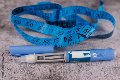 Blue measuring tape and glucose control pen with semaglutide on a concrete table.