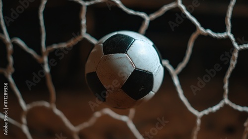 Sport ball break impact dynamic force. A soccer ball is caught in the net, symbolizing a goal scored in a match, with a focus on the ball and the netting.