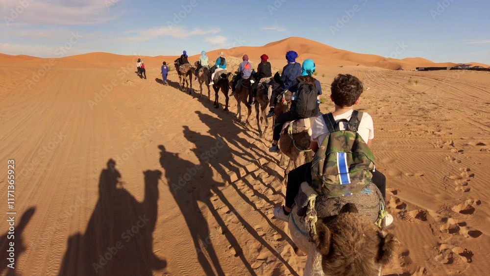 Caravan going through the sand dunes in the Sahara Desert, Morocco - Merzuga - tourist visit the desert on camels during the holidays - adventure and freedom during a trip , safari - organized travel